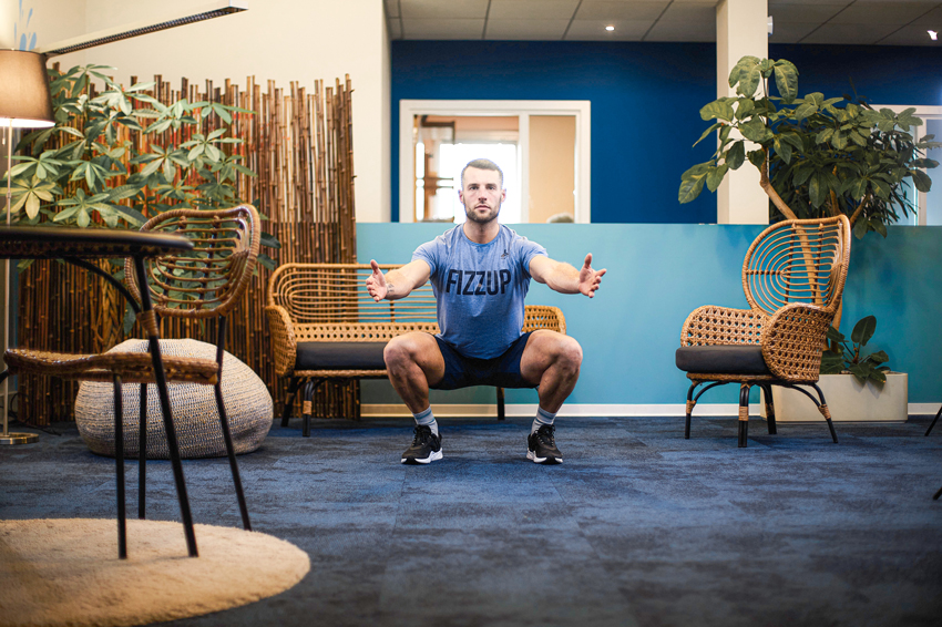 Homme faisant des squats dans son salon pour lutter contre le stress