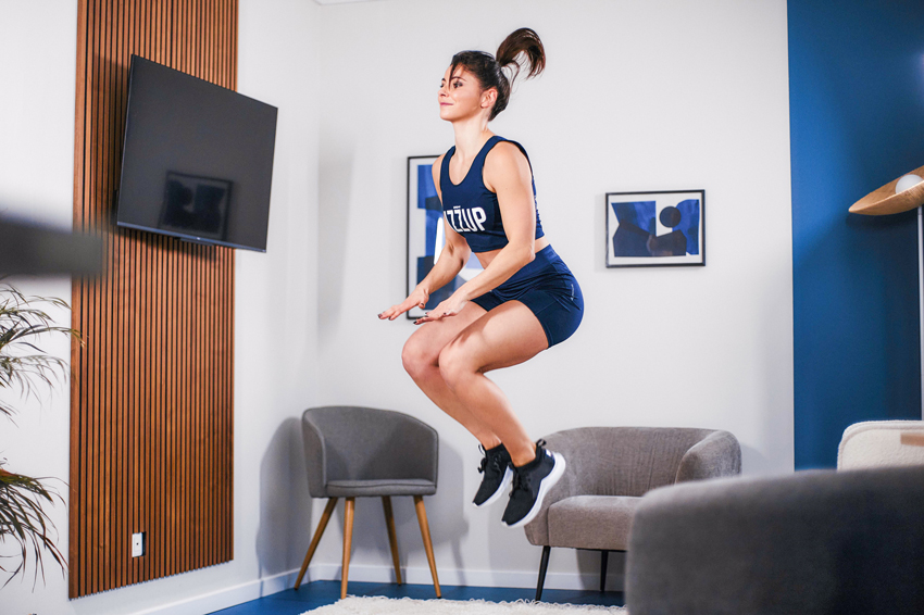 Femme en tenue de sport dans un salon effectuant un saut