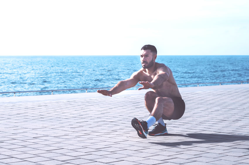 Homme effectuant un pistol squat, exercice phare de la callisthénie, au bord de l'eau